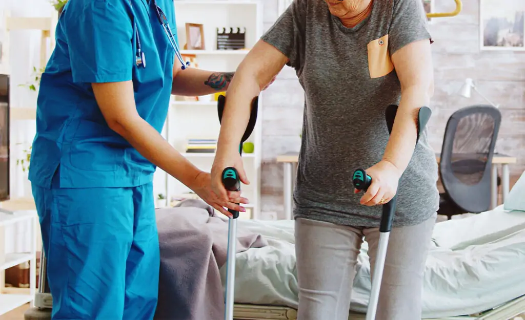 Physiotherapist supporting a patient through a mobility exercise at home